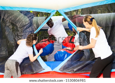 Gambling friends boxing giant gloves on an inflatable trampoline in an amusement park