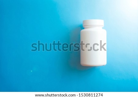 Closeup of white pill bottle on blue background.Health care, medical concept.
