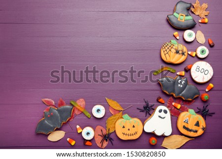 Halloween gingerbread cookies with dry leafs on purple wooden table