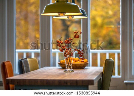 Autumn interior still life scene with red berries, oranges and yellow foliage background