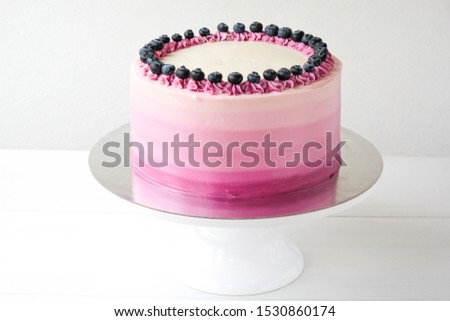 Birthday cake with blueberries and purple gradient cream on white background. Picture for a menu or a confectionery catalog.