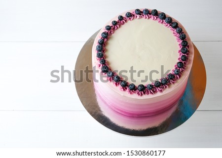Birthday cake with blueberries and purple gradient cream on white background. Picture for a menu or a confectionery catalog. Top view.