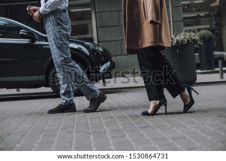 Cropped photo of a man and a woman walking on the paved road