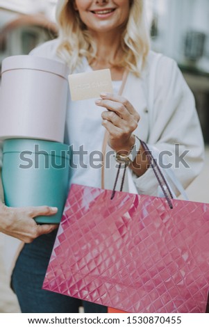 Cropped photo of a smiling female holding her shopping bags and a credit card