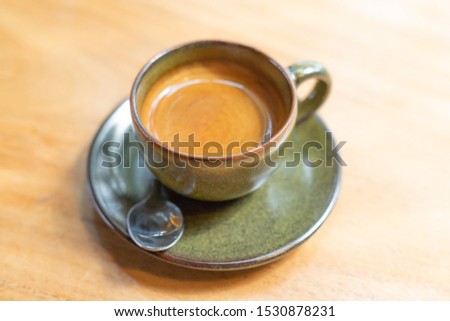 Dark green coffee espresso cup  on a brown wooden table in the middle of the picture