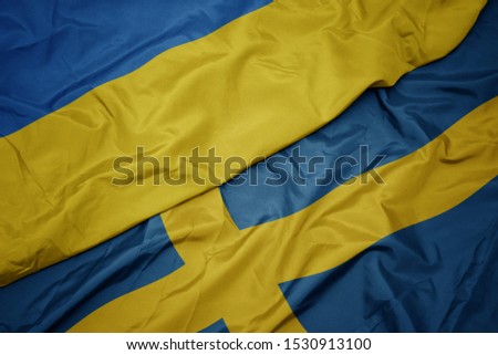 waving colorful flag of sweden and national flag of ukraine. macro