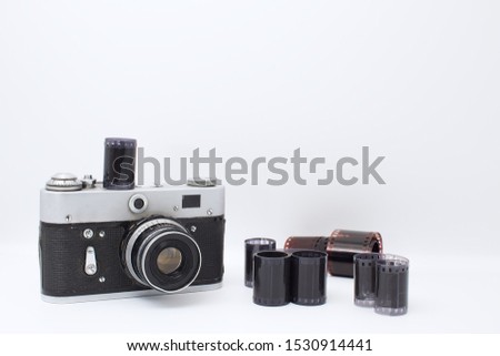 Old camera on a white background. The film lies next to the camera. The history of photography and the work of the photographer.