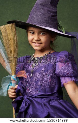 Cute child girl in witch costume for Halloween, close-up. Happy sisters on Halloween. Funny kids in carnival costumes on green background with copy space