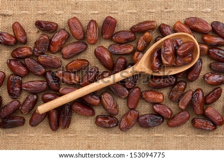 Wooden spoon with date   lying on sackcloth Royalty-Free Stock Photo #153094775