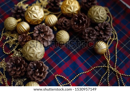 Flat lay of christmas decorations like pine cones and golden balls on the blue-red plaid background. Photo with copy space. New year concept.