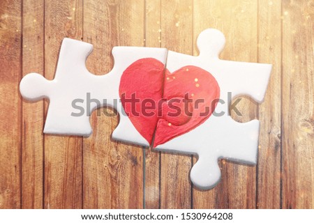 Puzzle pieces with painted red heart isolated on white background
