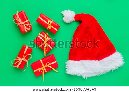 Gift boxes with santa hat on green background