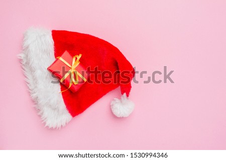 Gift box with santa hat on pink background