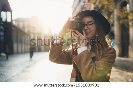 Photographer in glasses take photo on retro camera. Tourist portrait. Girl in hat in Barcelona holiday. Sunlight flare street in europe city. Traveler hipster shooting architecture, copy space mockup