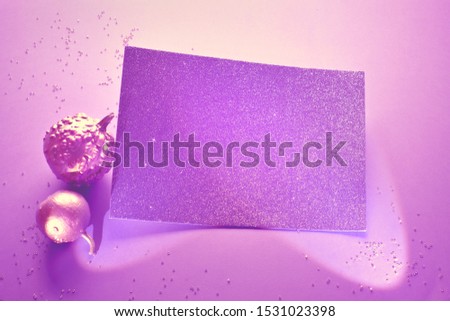 Creative purple Halloween background with two decorative pumpkins painted metallic pink and glittering paper card in spotlights with copy-space