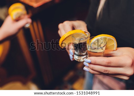 Friends toasting with shot glasses above an old wooden table black background.