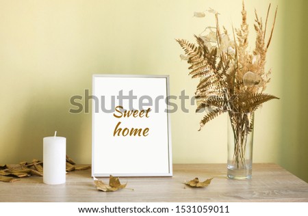 Dry yellow and golden flowers in vase, candle and picture frame Sweet Home. Home Decoration details. Design of interior.
