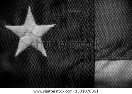 Close up of red white and blue American flag with an embroidered star and stitching in color and black and white