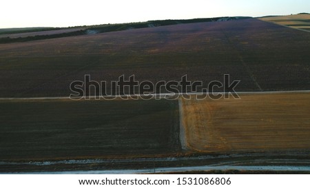 Aerial view of large fields near the countryside road against the blue sky in evening. Shot. Beautiful countryside landscape