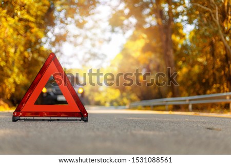 Red triangle, red emergency stop sign, red emergency symbol and black car stop and park on road.