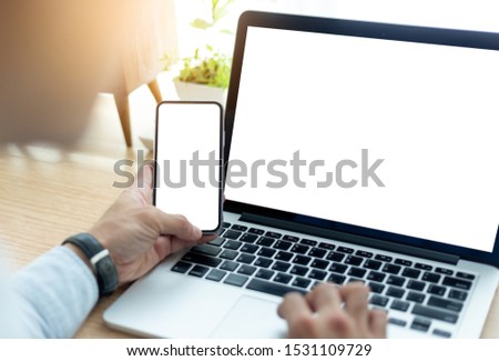 mockup image blank screen computer,cell phone with white background for advertising text,hand man using laptop texting mobile contact business search information on desk in office.marketing,design 