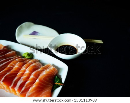 Top view picture of Salmon sashimi on white plate isolated on black texture background.