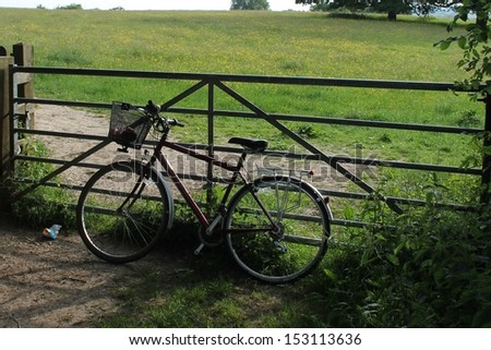 cycling farm gate bicycle cycle with basket leaning against old field gate in countryside UK stock, photo, photograph, image, picture, 
