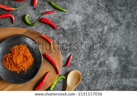 Top view of red and green chilli, chilli powder, plate and wooden board with copy space on stone table background