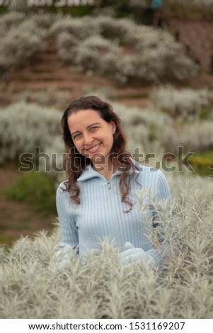 Portrait of young pretty woman wearing blue gloves and sweater. Happy Christmas and New Year celebration. Beautiful Caucasian woman with charming smile in edelweiss valley. Cold winter season.