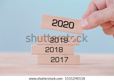 Hand holding chooses wooden block cubes with word 2020 , new year concept