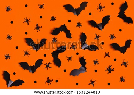 Halloween decoration concept - orange background with spiders, bats. Flat lay, top view.