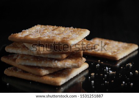 elegant low key photo with reflections of biscuit piles with black background on the floor, sprinkles of sugar from biscuits 