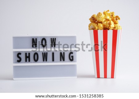 Now Showing word on mini lightbox beside caramel popcorn for movies.