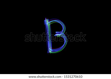 Long exposure photograph of the letter b in neon multi colour in an abstract swirl, parallel lines pattern against a black background. Light painting photography.