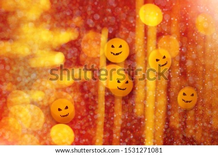 Festive blurry defocused abstract orange bokeh lights with evil pumpkin faces on shiny orange background. Halloween concept.