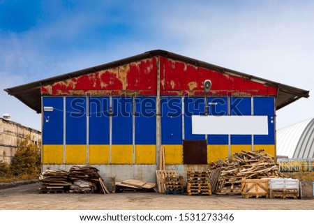 Close-up of the national flag of Armenia
 painted on the metal wall of a large warehouse the closed territory on a summer day. The concept of storage of goods, entry to a closed area, tourism