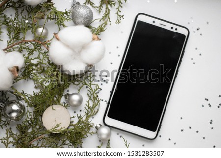 smartphone mockup with silver balls on white table and fir branches. minimalistic Christmas background and cotton flowers. candle