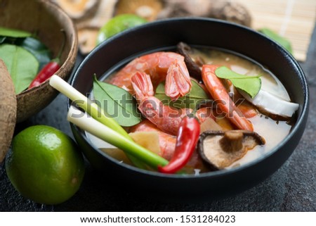 Close-up of a black bowl with traditional thai Tom Yum soup, selective focus