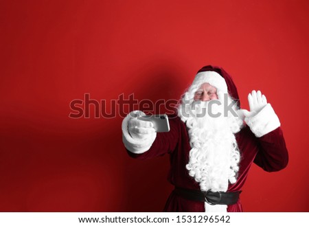 Authentic Santa Claus taking selfie on red background. Space for text