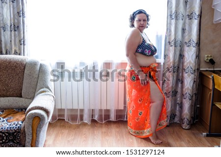 pictured in the photo plump woman in a purple swimwear and orange pareo