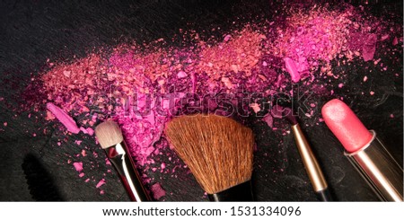 A panorama of make-up brushes, lipstick, and crushed cosmetics, shot from the top on a black background with a place for logo, a beauty design template for a makeup banner