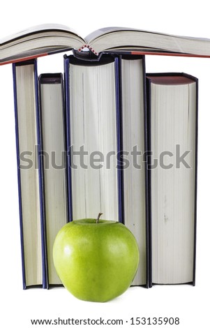A stack of school books with a green apple sitting in front.