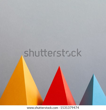 Abstract colorful geometrical background. Three-dimensional prism pyramid objects on gray. Yellow red blue colored solid figures, soft focus photo. Copy space