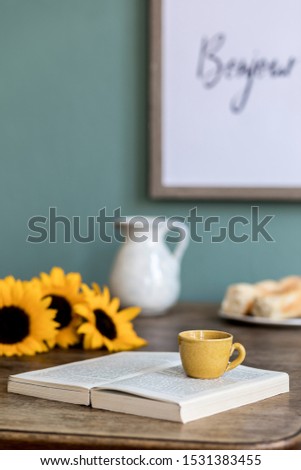 Stylish and cozy interior of kitchen space with wooden table beautiful sunflowers, cup of coffee, book and flower. Scandinavian decor of interior with kitchen accessories. Template. 
