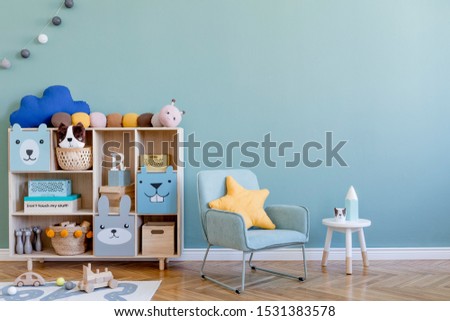 Scandinavian nursery room with wooden cabinet, mint armchair, natural teddy bears and plush animal toys. Cute modern interior of playroom with eucalyptus walls, baby accessories and toys. Copy space.