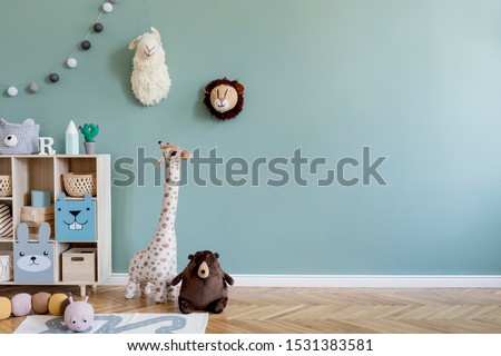Interior design of scandinavian childroom with wooden cabinet, a lot of plush and wooden toys and accessories. Eucalyptus color of background walls. Plush animal head on the wall. Template Copy space