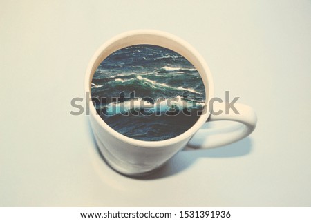 White cup with water. Sea. Ocean. Sea waves. Creative postcard.