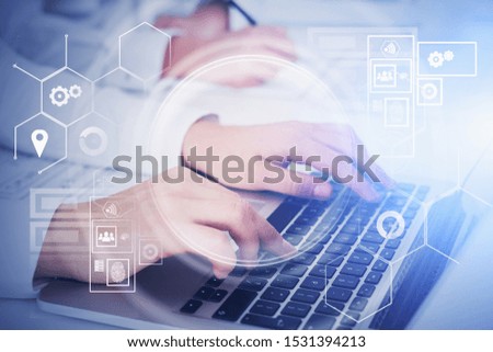 Hands of women typing on laptop in office with double exposure of HUD digital interface. Concept of programming and internet of things. Toned image