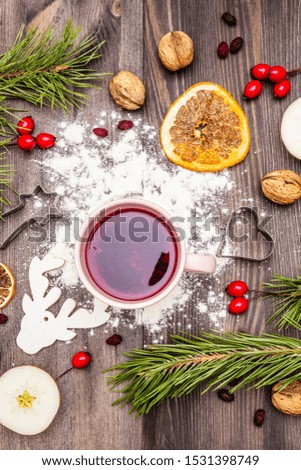 Christmas hot tea background. New Year mood, evergreen pine, nuts, berries, apples, orange. Cookie cutters, flour, deer. Wooden boards, top view
