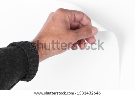 man's hand pull up  a bottom corner of a white paper sheet to uncover a neutral foreground with clipping path and copy space for your text